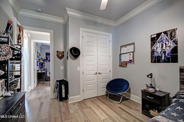 bedroom featuring ornamental molding, light wood-style floors, a closet, baseboards, and a ceiling fan