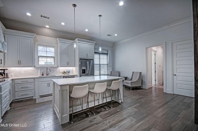 kitchen with stainless steel fridge with ice dispenser, a center island, tasteful backsplash, a sink, and white cabinets