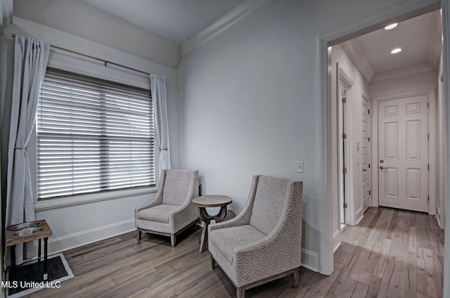 living area featuring ornamental molding, baseboards, and wood finished floors