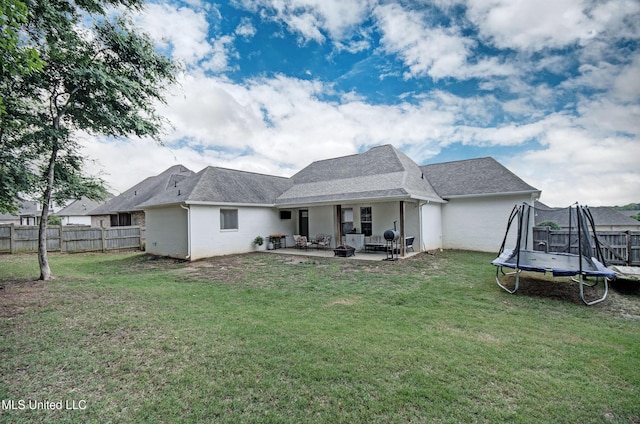 back of property featuring a trampoline, a patio, and stucco siding