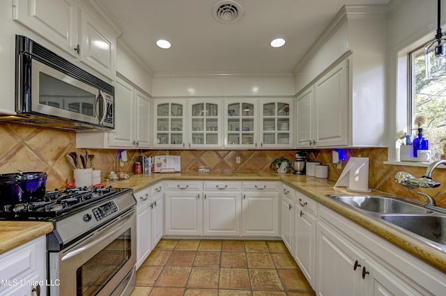 kitchen featuring appliances with stainless steel finishes, sink, white cabinets, and backsplash