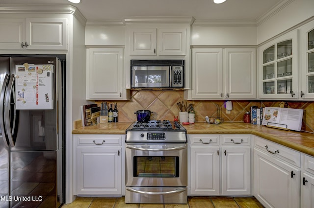 kitchen with white cabinetry, ornamental molding, appliances with stainless steel finishes, and tasteful backsplash