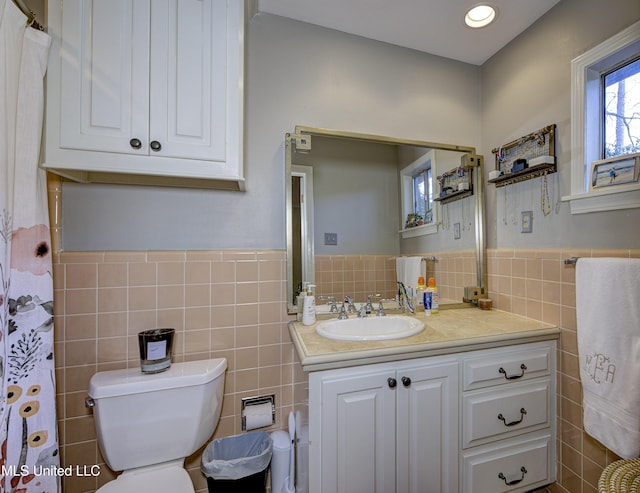 bathroom with vanity, tile walls, and toilet