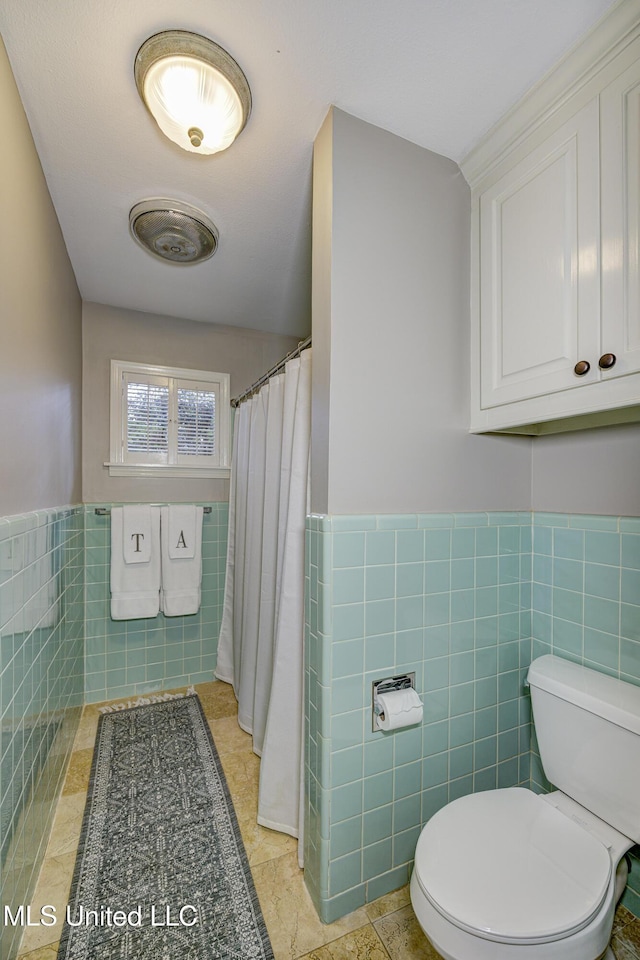 bathroom featuring tile walls, curtained shower, and toilet