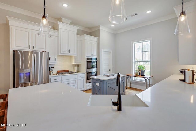 221 Lost Oak Ln, Brandon, MS 39047 - kitchen with appliances with stainless steel finishes, a kitchen island, a sink, tasteful backsplash, and light countertops