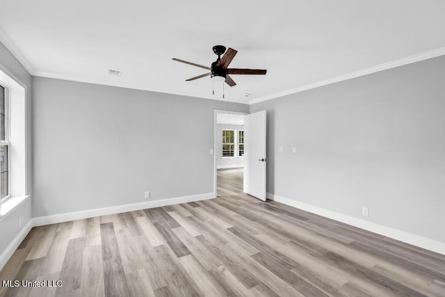 spare room with crown molding, wood finished floors, ceiling fan, and baseboards