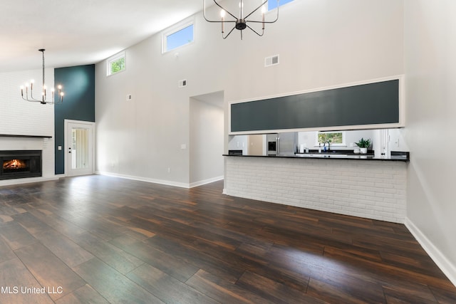 3106 Breezy Hill Ln, Ocean Springs, MS 39564 - unfurnished living room with a chandelier, a towering ceiling, hardwood / wood-style floors, and a fireplace