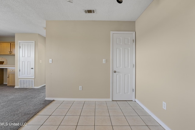 unfurnished room featuring visible vents, light colored carpet, a textured ceiling, and baseboards