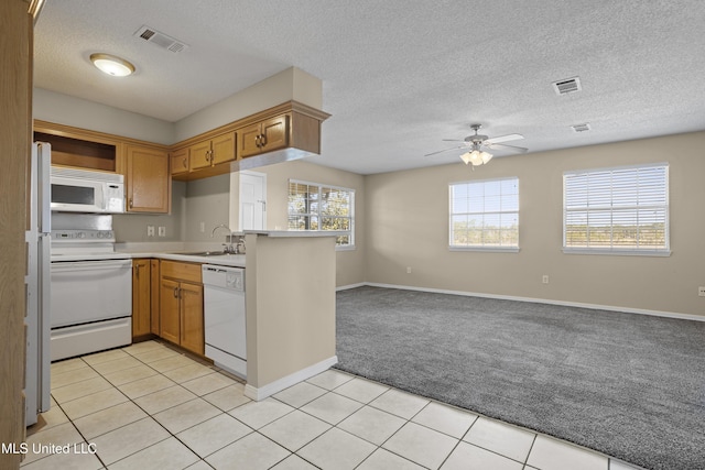 kitchen featuring light carpet, visible vents, white appliances, and a sink