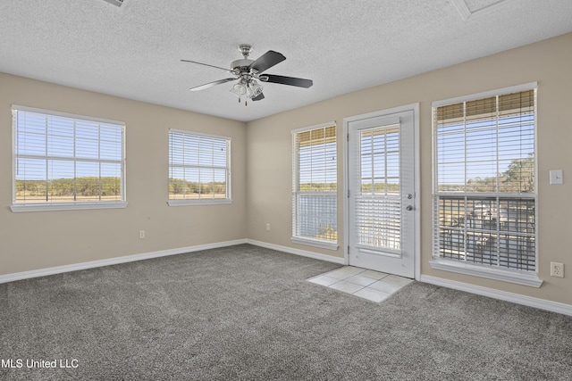 carpeted spare room featuring ceiling fan, baseboards, and a textured ceiling