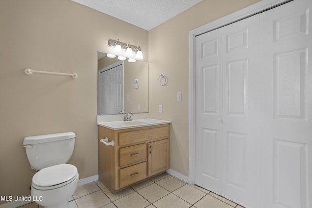 bathroom with baseboards, toilet, vanity, tile patterned floors, and a textured ceiling