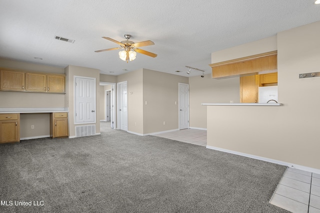 unfurnished living room featuring a textured ceiling, tile patterned floors, visible vents, and built in study area