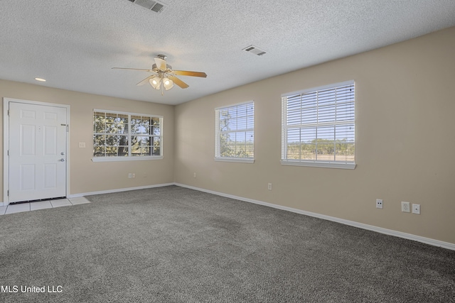 carpeted spare room featuring a textured ceiling, baseboards, visible vents, and ceiling fan