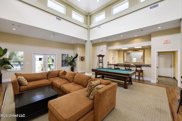 game room featuring light wood-type flooring, visible vents, french doors, baseboards, and a towering ceiling