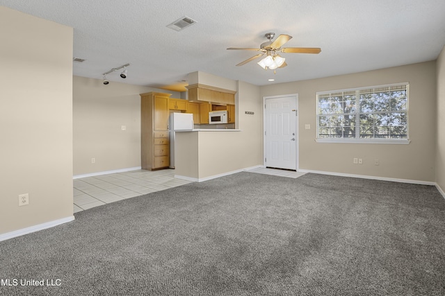 unfurnished living room featuring visible vents, ceiling fan, light carpet, light tile patterned floors, and a textured ceiling