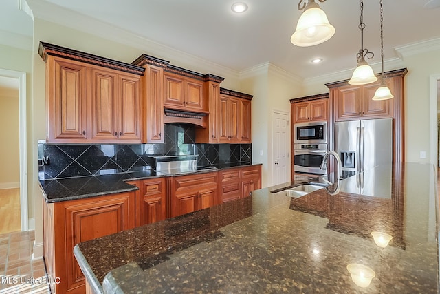 kitchen featuring dark stone counters, stainless steel appliances, crown molding, sink, and hanging light fixtures