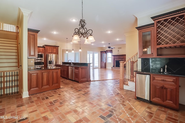 kitchen with sink, hanging light fixtures, decorative backsplash, ceiling fan with notable chandelier, and appliances with stainless steel finishes