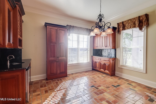 kitchen with backsplash, crown molding, a healthy amount of sunlight, and a notable chandelier