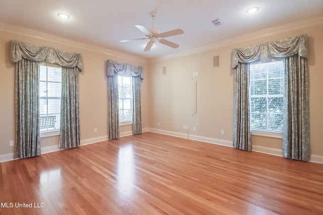 empty room with plenty of natural light, light wood-type flooring, and crown molding