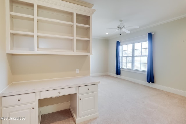 unfurnished office featuring light carpet, built in desk, ceiling fan, and ornamental molding