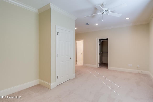 unfurnished bedroom with ceiling fan, a spacious closet, light colored carpet, a closet, and ornamental molding