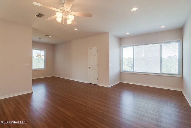 spare room with ceiling fan with notable chandelier and dark wood-type flooring