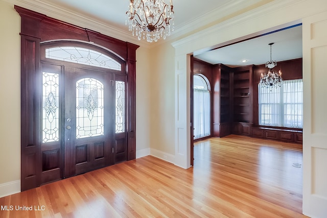 foyer entrance featuring an inviting chandelier, ornamental molding, and light hardwood / wood-style flooring