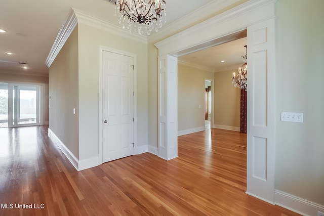 hall with a chandelier, hardwood / wood-style floors, and crown molding