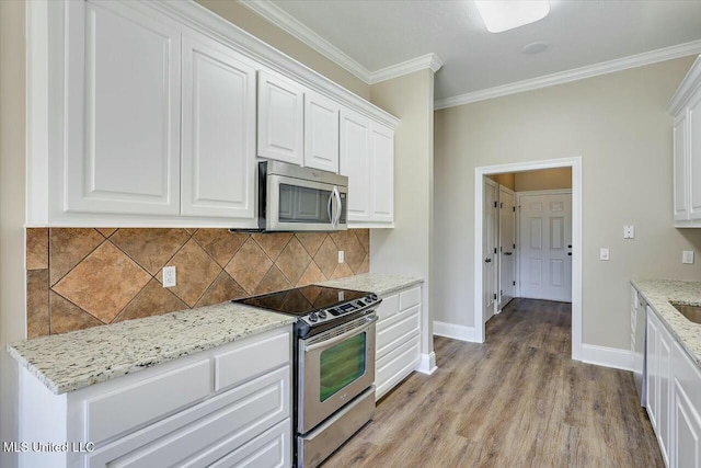 kitchen featuring crown molding, stainless steel appliances, decorative backsplash, light wood-style floors, and white cabinetry