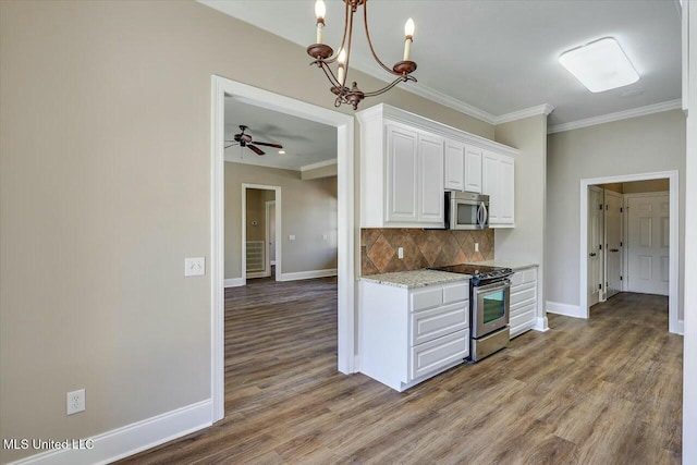 kitchen featuring wood finished floors, stainless steel appliances, crown molding, white cabinetry, and backsplash