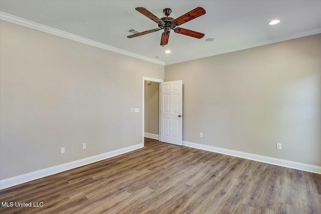 spare room with visible vents, ornamental molding, a ceiling fan, wood finished floors, and baseboards