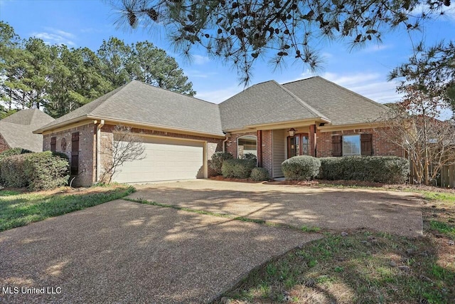 view of front of home with an attached garage, a shingled roof, concrete driveway, and brick siding