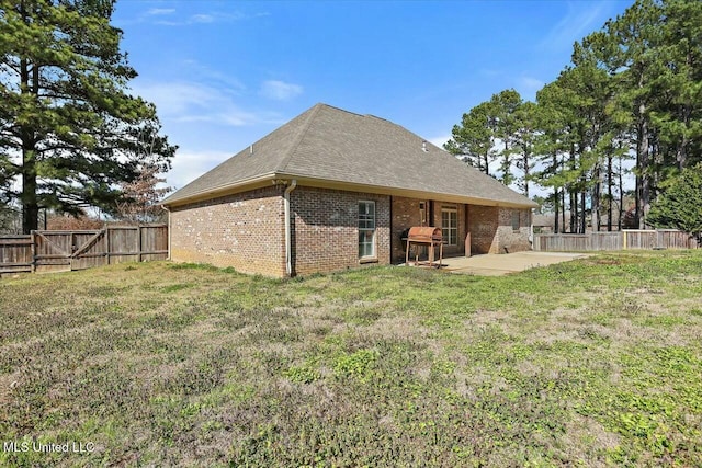 back of house with a yard, a patio, brick siding, and a fenced backyard