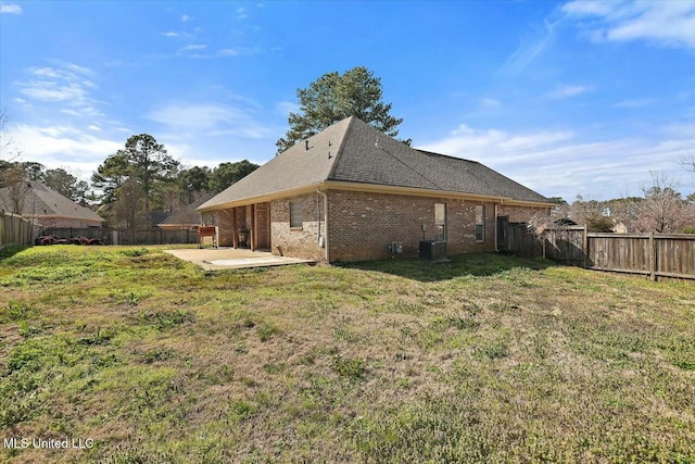 rear view of property featuring a patio area, a fenced backyard, brick siding, and a yard