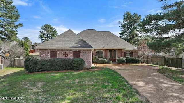 view of front of property featuring central AC, brick siding, a shingled roof, fence, and a front yard