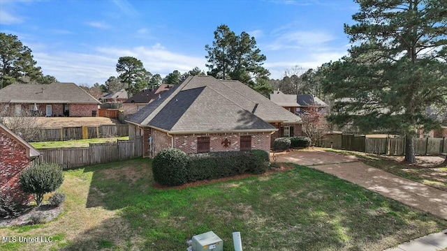 view of front of property with a shingled roof, a front yard, fence, and brick siding