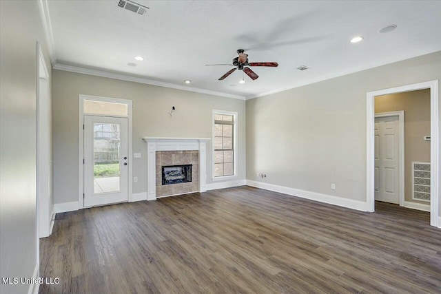 unfurnished living room featuring dark wood-type flooring, a tiled fireplace, visible vents, and a healthy amount of sunlight