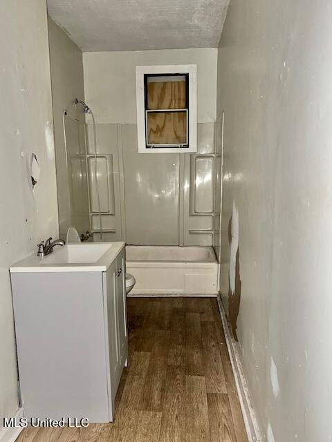 721 Adams St, Vicksburg, MS 39183 - bathroom with toilet, vanity, bathing tub / shower combination, wood finished floors, and a textured ceiling