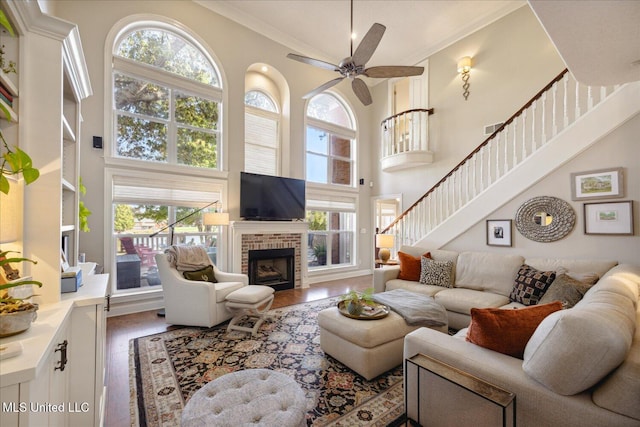 living room featuring a towering ceiling, a fireplace, wood-type flooring, and crown molding