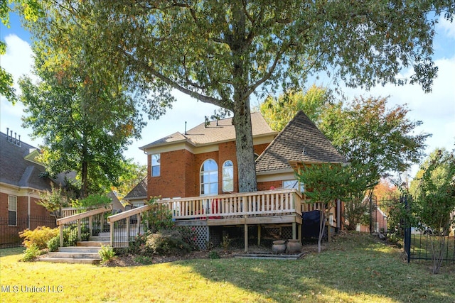 rear view of property featuring a wooden deck and a lawn