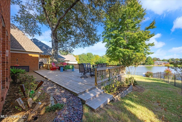 wooden deck featuring a water view and a lawn