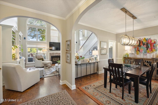 dining room featuring a high ceiling, ornamental molding, a textured ceiling, a fireplace, and dark wood-type flooring