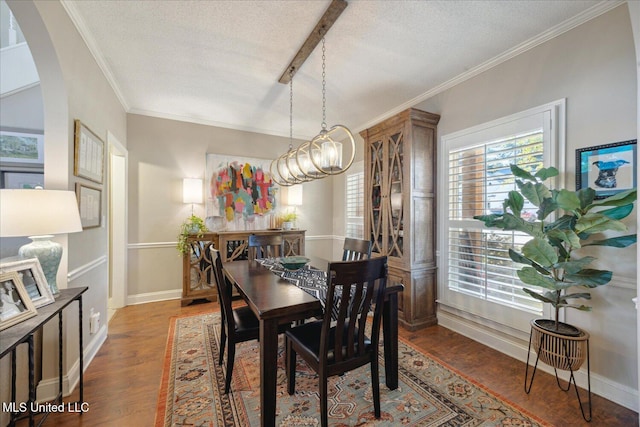 dining room featuring dark wood-type flooring, a textured ceiling, a notable chandelier, and ornamental molding