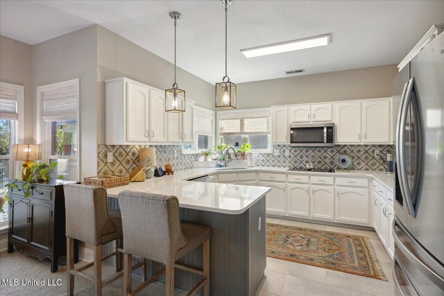 kitchen with a wealth of natural light, stainless steel appliances, kitchen peninsula, and a breakfast bar area