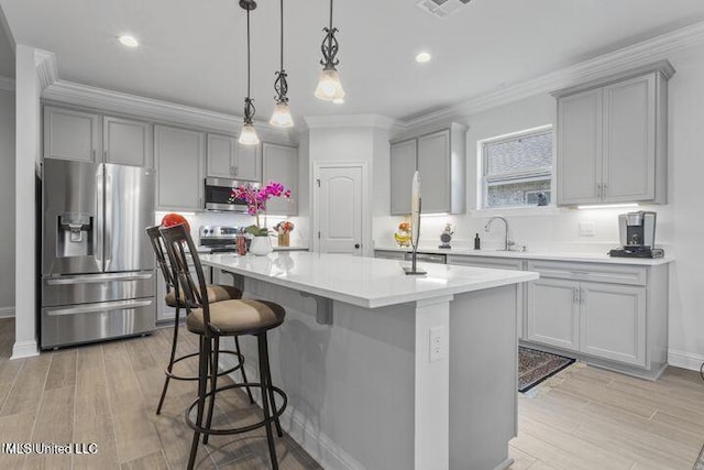 kitchen featuring crown molding, appliances with stainless steel finishes, a sink, and gray cabinetry