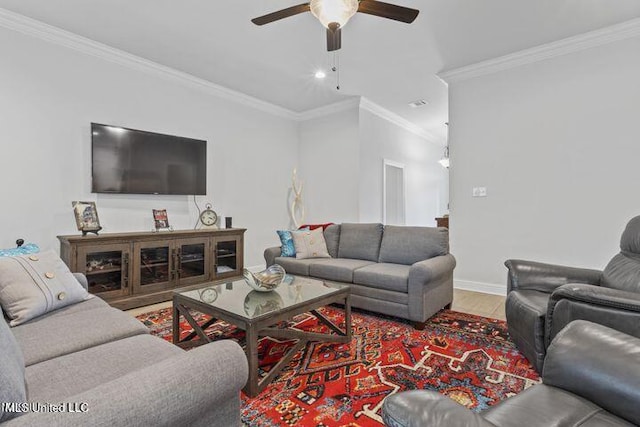 living area with baseboards, ceiling fan, wood finished floors, and crown molding