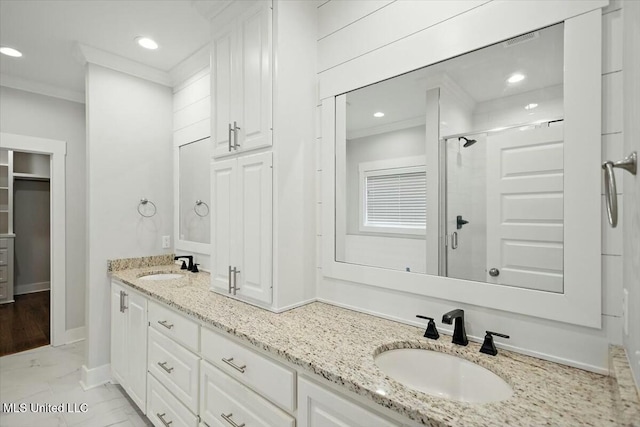 bathroom with ornamental molding, a shower with shower door, and vanity