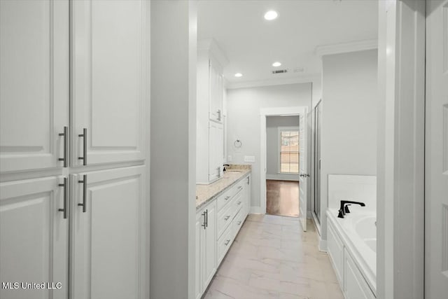 bathroom featuring vanity, ornamental molding, and a tub