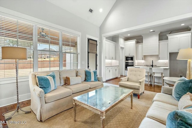 living room with high vaulted ceiling and light hardwood / wood-style floors