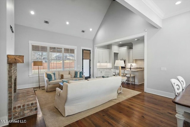 living room featuring a fireplace, dark wood-type flooring, high vaulted ceiling, and sink